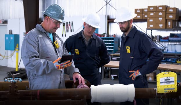 Field technicians reviewing PWHT services and preheat weld treatment and on a pipe.